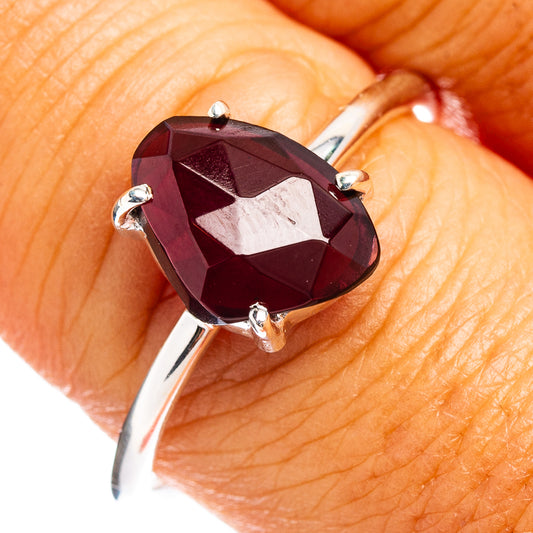 Faceted garnet ring with dark red oval gemstone, four silver prongs
