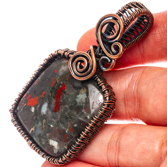 Bloodstone wire wrap pendant with oxidized copper spirals, close-up on dark stone
