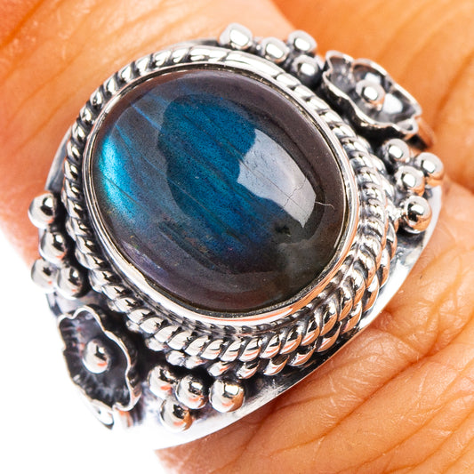 Sterling silver labradorite ring on finger with oval cabochon, vivid blue flash, ornate border