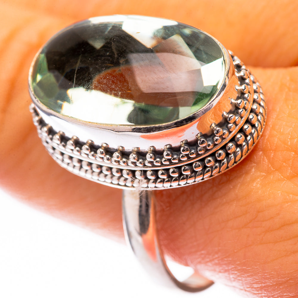 Oval faceted green gemstone ring with ornate silver beaded halo setting