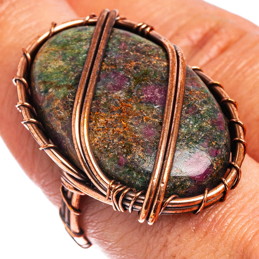 Oxidized copper wire wrap ring on hand, oval green and purple speckled stone.