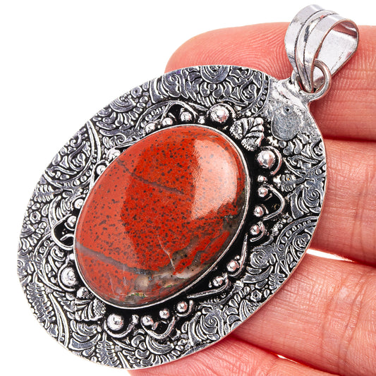 Red jasper oval pendant with ornate German silver filigree and metal bail