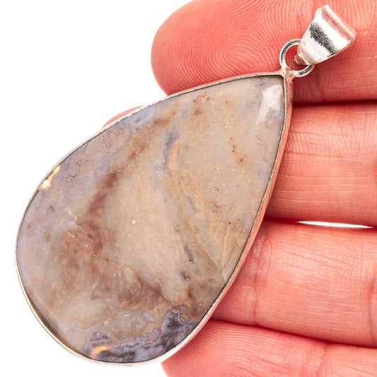 Silver-plated teardrop rhyolite pendant with close-up stone on hand