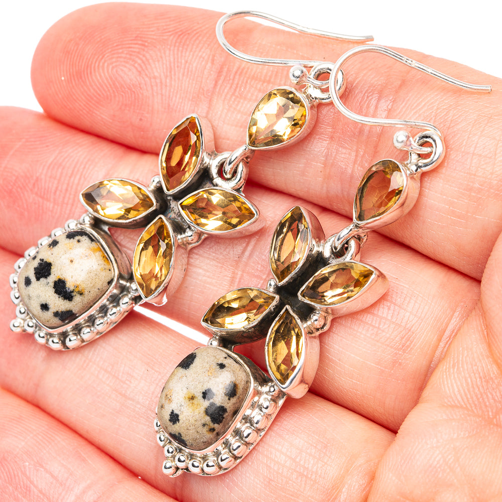 Silver dangle earrings on hand: yellow petal stones with speckled jasper oval drops