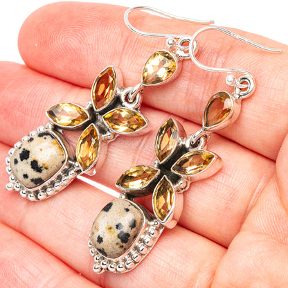 Silver dangle earrings on hand: yellow petal stones with speckled jasper oval drops