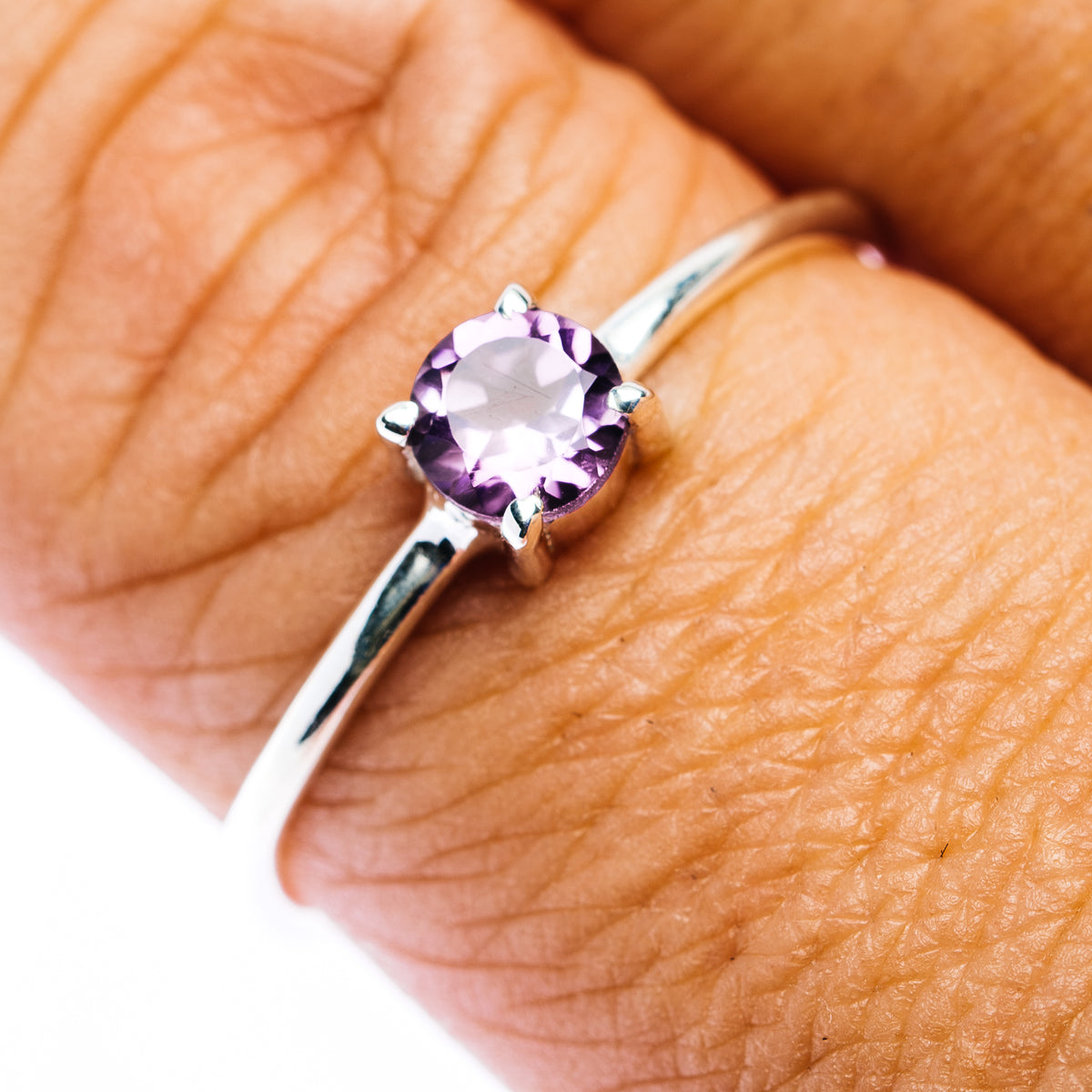 Amethyst sterling silver ring with round purple gemstone, close-up on hand