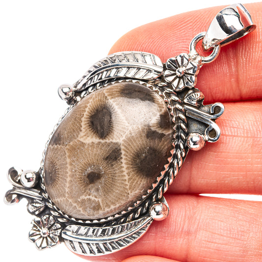 Oval sterling silver pendant with fossil coral cabochon and ornate floral settings