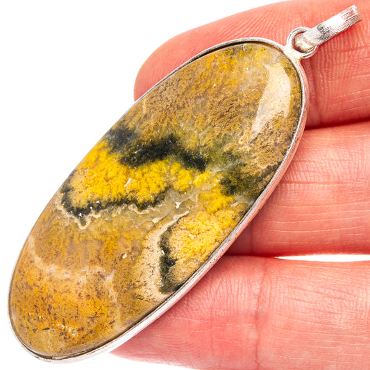 Bumblebee jasper pendant close-up on hand, oval silver-plated frame with yellow and dark veining