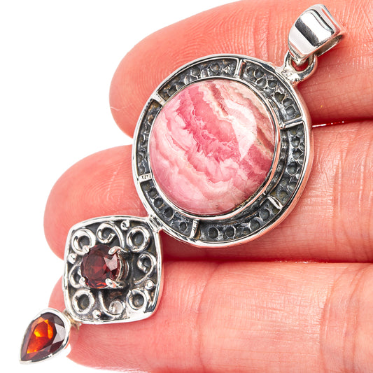 Sterling silver pendant with round pink rhodochrosite cabochon and garnet accents
