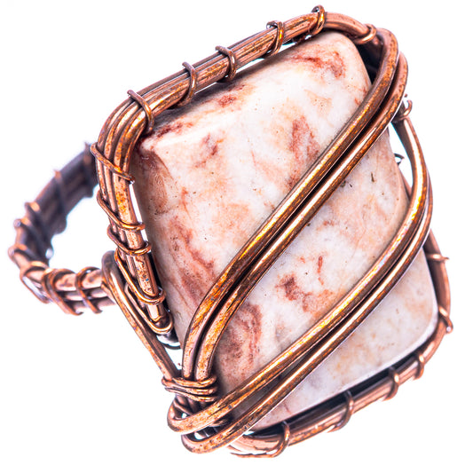 Oxidized copper wire ring holding speckled jasper cabochon, ornate split band