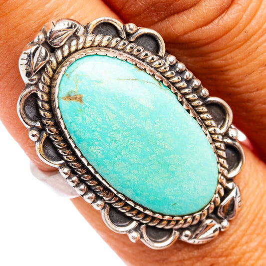 Turquoise oval cabochon silver ring with scalloped rope edge detail, worn on finger