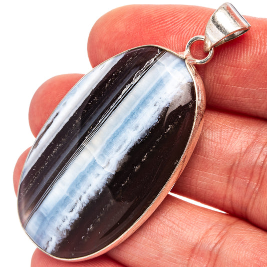 Silver-plated oval opal pendant with dark black and blue striped stone and bail loop