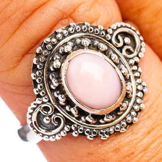 Pink opal sterling silver ring on finger, oval pink gemstone in detailed filigree bezel