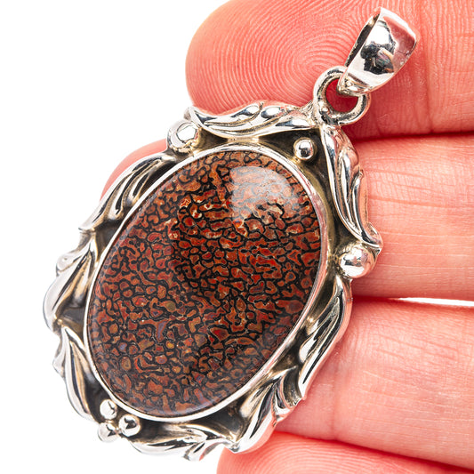 Sterling silver dinosaur bone pendant with oval red-brown textured stone in ornate frame