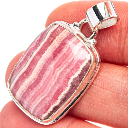 Close-up oval rhodochrosite pendant: pink striped stone in sterling silver bezel, bail