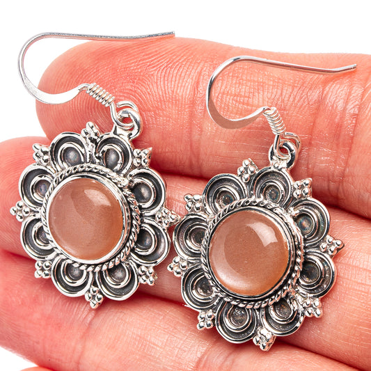 Orange-peach cabochon earrings in silver-tone floral filigree with fishhook hooks.