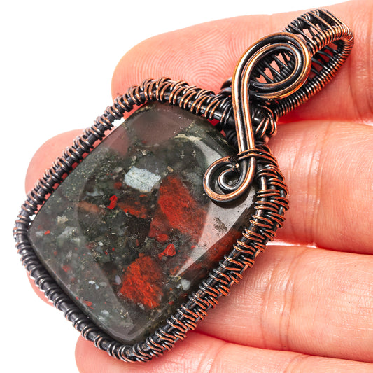 Oxidized copper wire-wrap pendant with dark red-and-green bloodstone cabochon, close-up