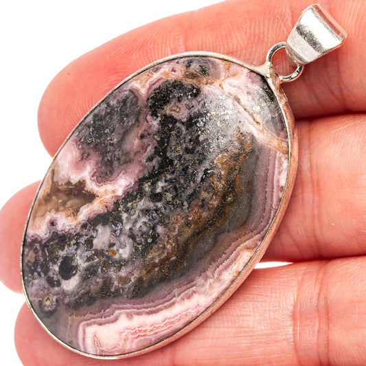 Rhodochrosite pendant in silver-plated bezel, oval cabochon with pink, gray, and black bands