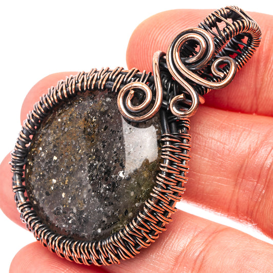 Oxidized copper wire-wrapped pendant with dark speckled round stone, swirl setting