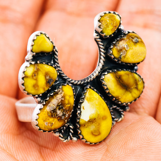 Sterling silver naja ring with yellow cabochon stones on a hand, side view