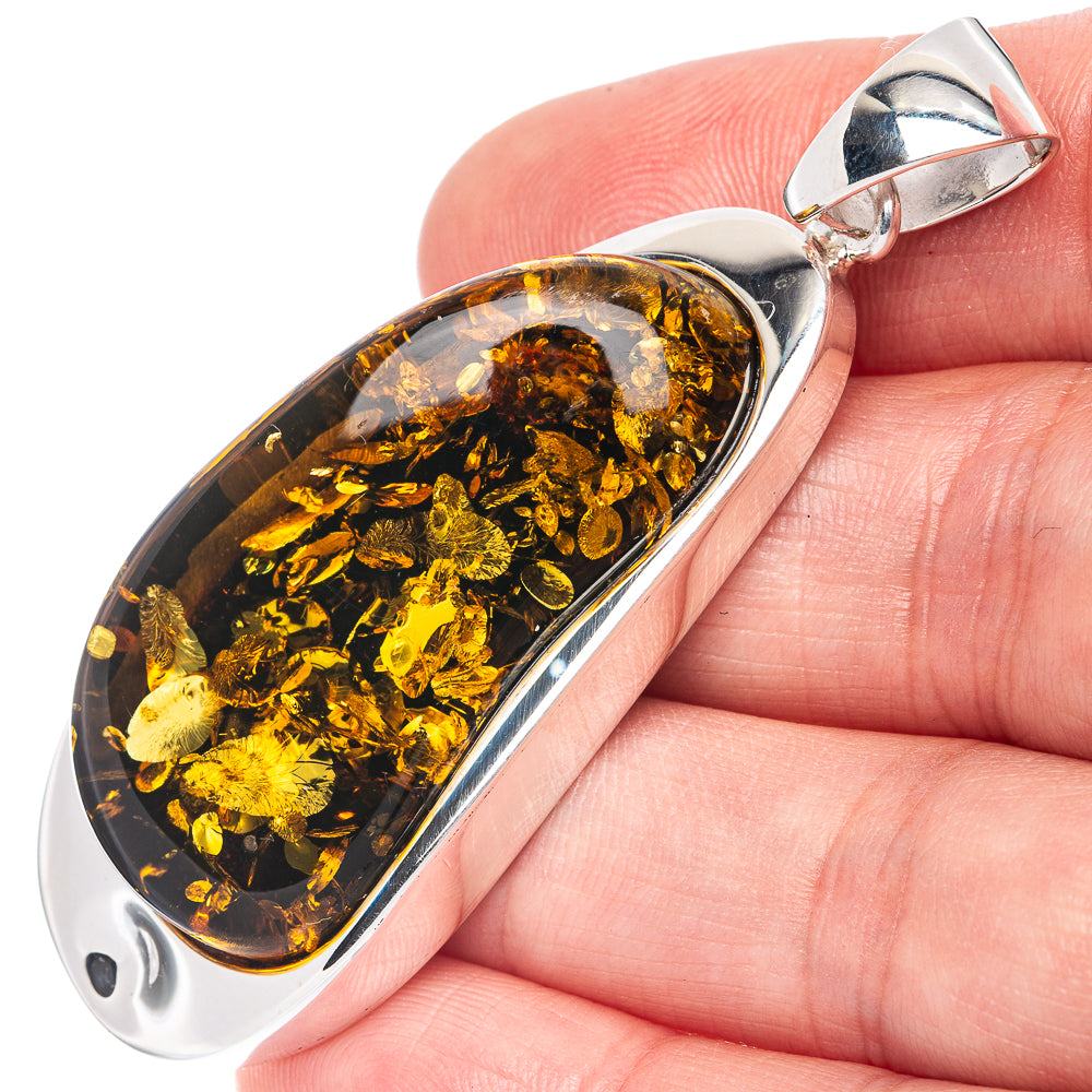 Baltic amber oval pendant on 925 sterling silver bail, held in hand