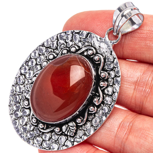 German silver pendant with oval red-orange carnelian cabochon and ornate border bail