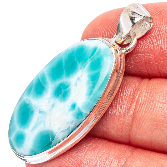 Oval turquoise-blue larimar pendant in sterling silver bezel, shown close on finger