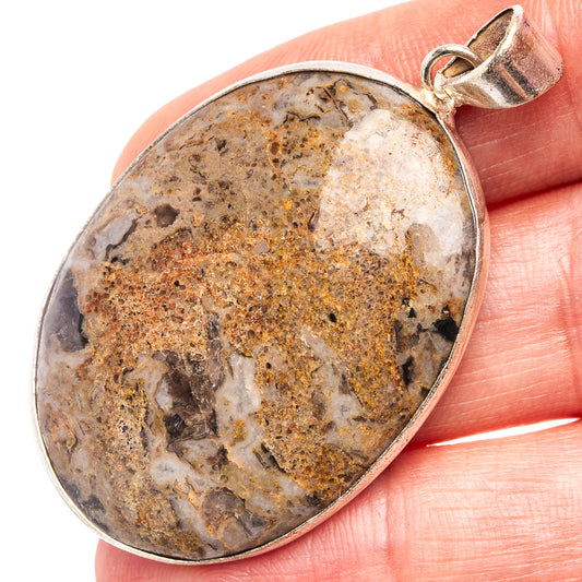 Silver-plated oval agate pendant with open bail, held in hand