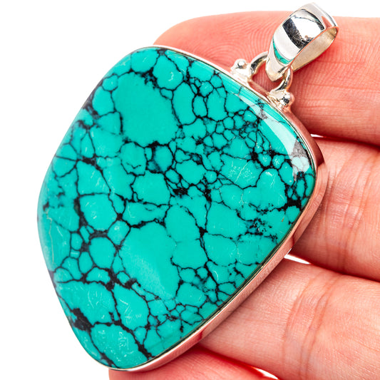 Turquoise teardrop pendant with black webbed pattern, silver frame and top bail