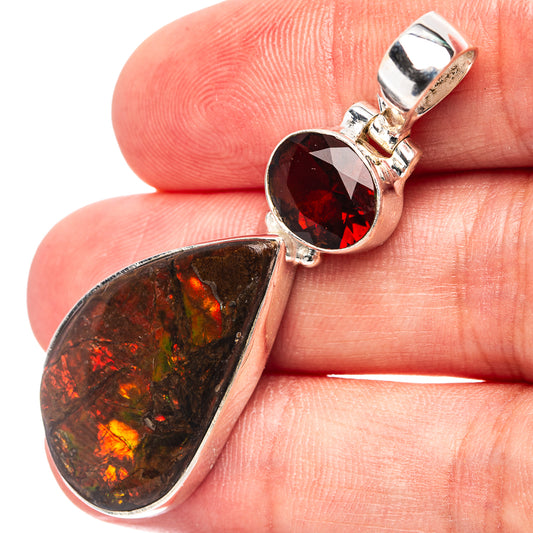 Close-up sterling silver pendant with red faceted gemstone and ammolite teardrop