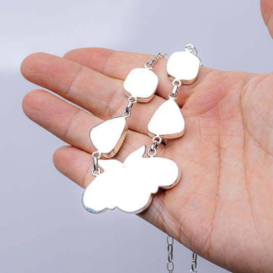 Turquoise stone necklace charms on silver chain, shown in hand