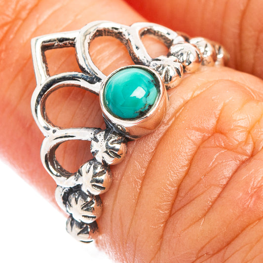 Turquoise oval gemstone bezel in ornate sterling silver crown ring, close-up.
