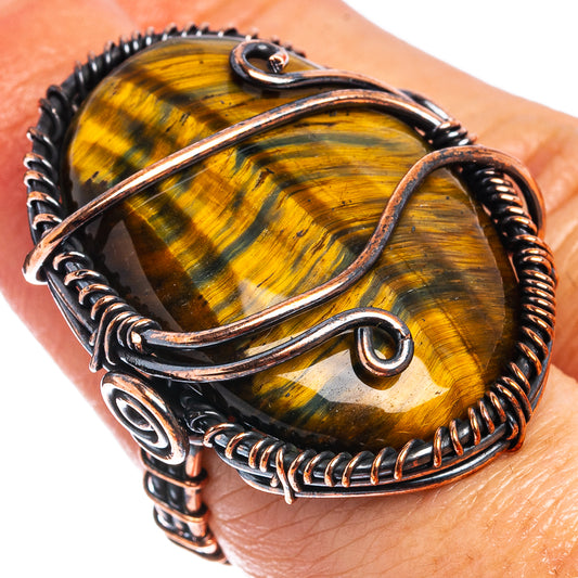Oxidized copper wire wrap ring with oval tiger's eye stone, swirl wire details.