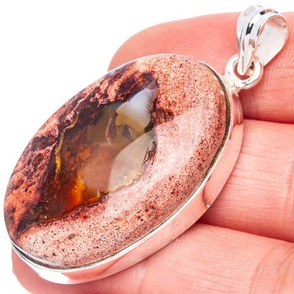 Oval fire opal pendant with warm amber center in sterling silver bezel, bail on top