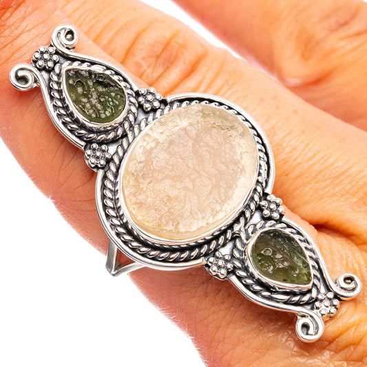 Silver-tone ring with oval amber center and two green stones, ornate bezel