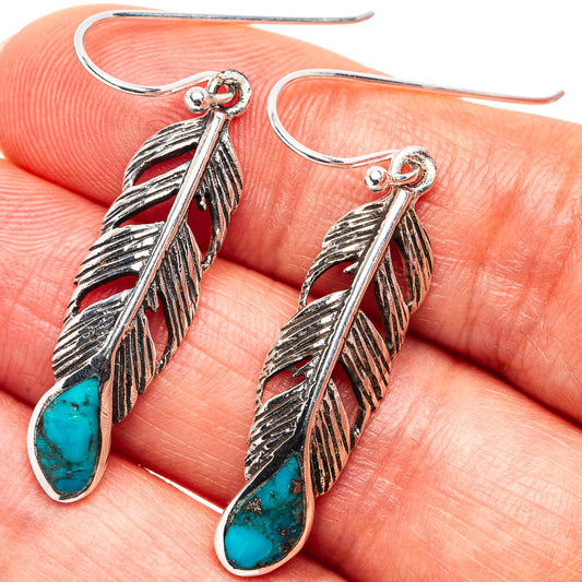Sterling silver feather earrings with turquoise teardrop stones, close-up view