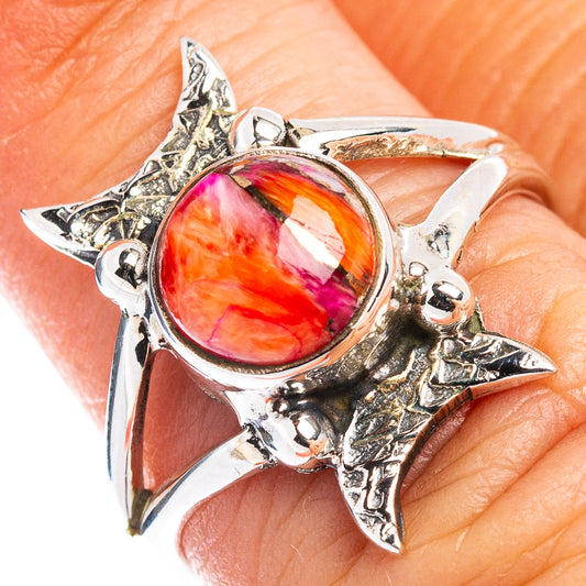 Sterling silver starburst ring with oval pink-red gemstone, ornate native-style setting.