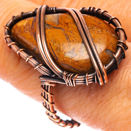 Oxidized copper ring on wrist with oval amber jasper stone wrapped in wire