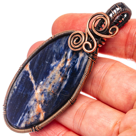 Sodalite wire wrap pendant with oxidized copper spiral frame on dark blue stone
