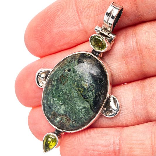 Oval blue-green galaxy jasper pendant in .925 sterling silver, held in hand for scale