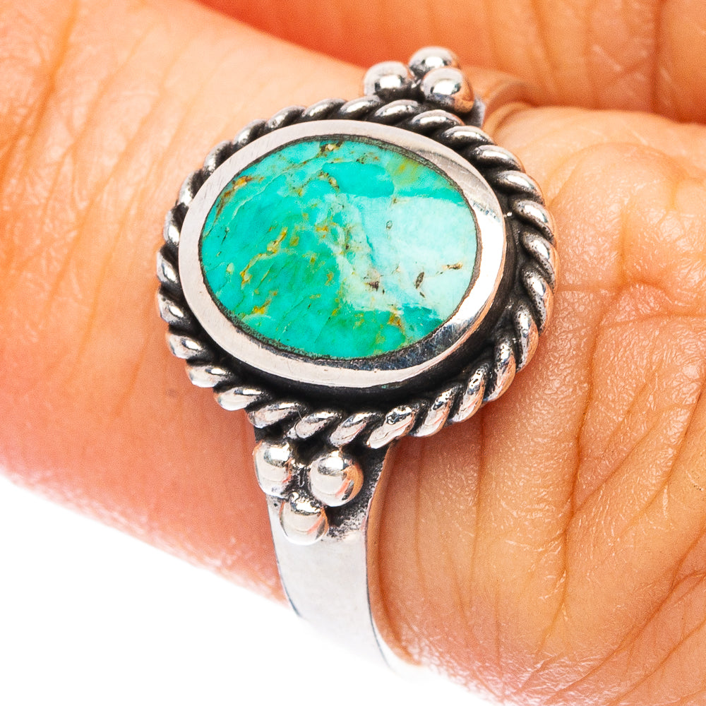 Turquoise oval gemstone ring in ornate sterling silver setting on finger