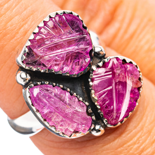 Carved ruby ring with three faceted purple-red stones and silver bezel setting