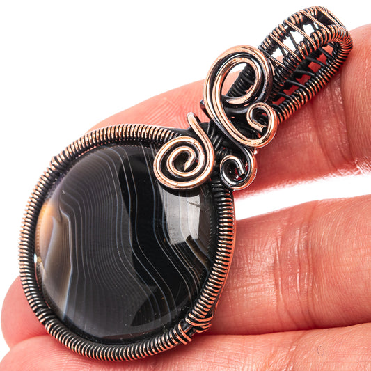Oxidized copper wire-wrap pendant with oval banded black agate and spiral bezel loops