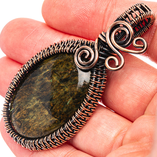 Close-up oval petersite wire wrap pendant with oxidized copper coils over dark stone