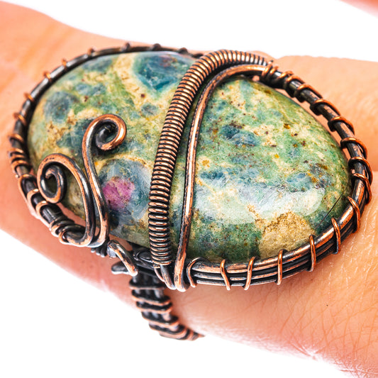 Copper wire wrap ring with oval mottled green-blue stone, on finger