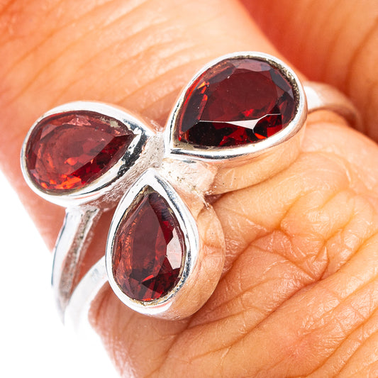 Close-up sterling silver ring with three faceted red garnet stones on teardrop settings