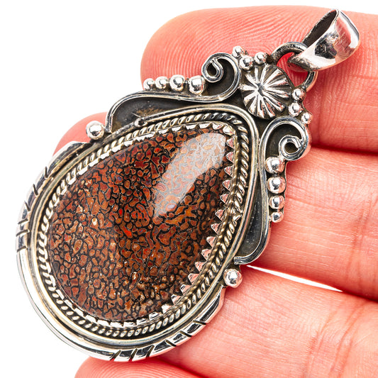 Oval .925 sterling silver dinosaur bone pendant, ornate bezel with red fossil inset