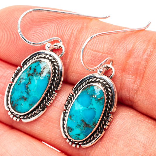 Close-up of oval turquoise stone earrings with silver rope bezel and hook backs.