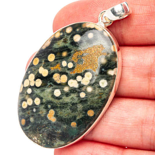 Oval ocean jasper pendant in sterling silver bezel; green, gold, and cream speckles.
