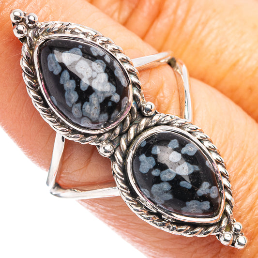 Sterling silver ring with twin oval dark cabochons and blue snowflake motif on finger